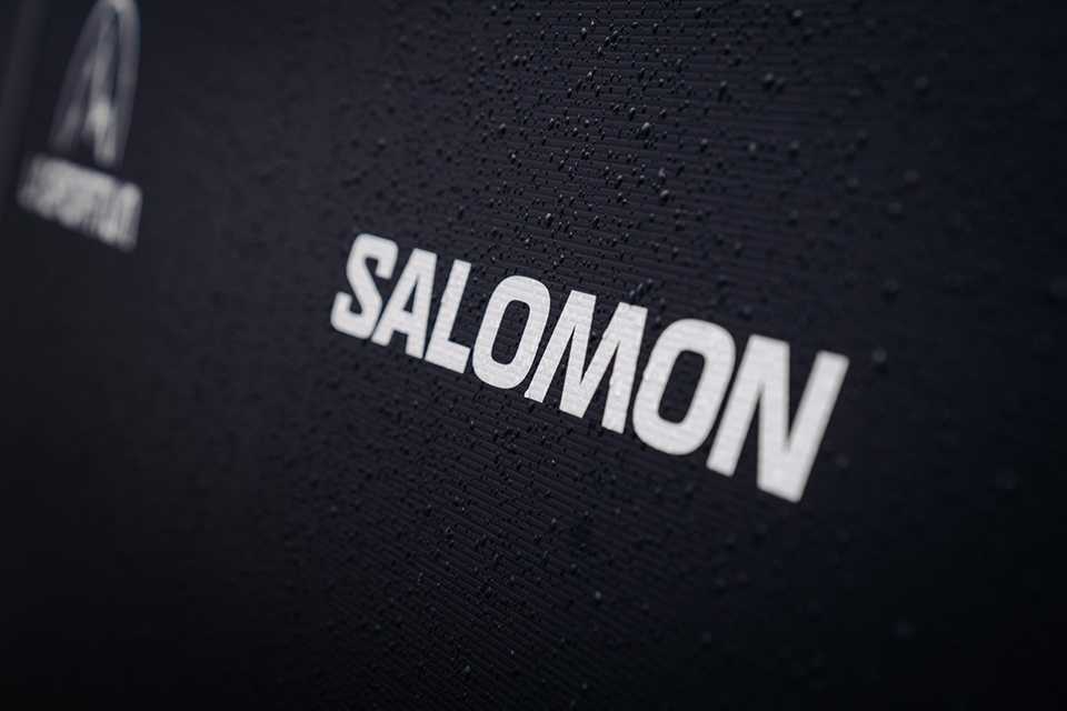 Salomon Logo auf dunklem Hintergrund mit Wassertropfen. Trail Run WM Innsbruck-Stubai.