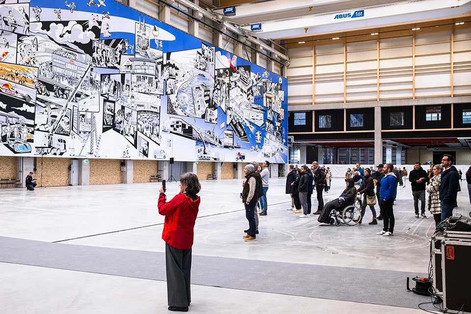 Red Bull Energy Station Oberwang: Besucher bewundern großes Wandbild in Halle. Kunstausstellung.