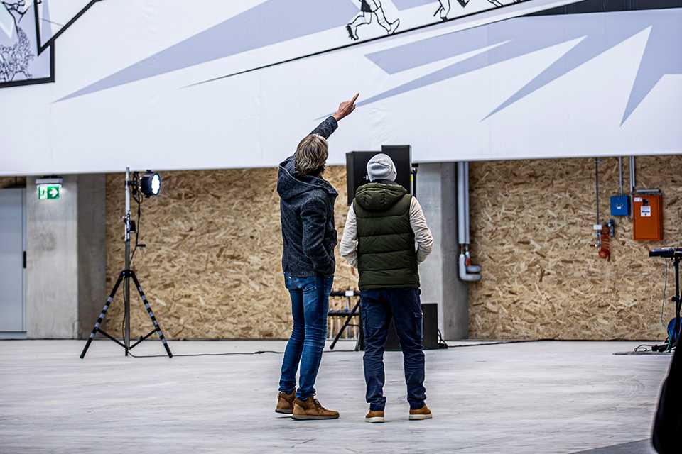 Red Bull Energy Station Department Oberwang: Zwei Personen betrachten Wandkunst in Halle.